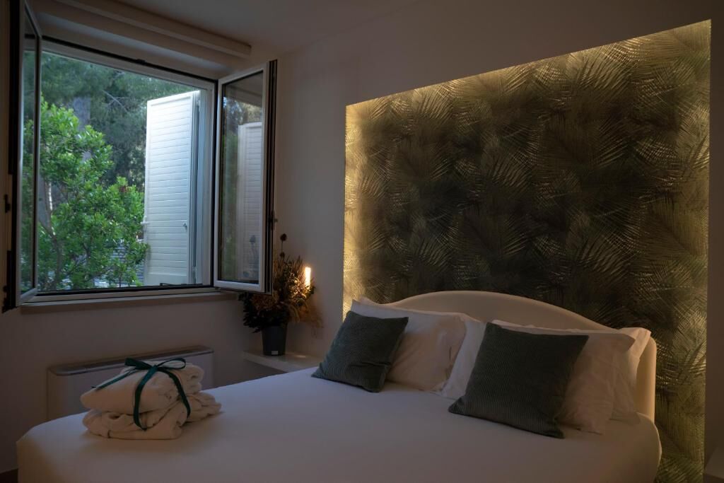 Ein Schlafzimmer mit einem Bett, einem Fenster und Blick auf Grünfläche.