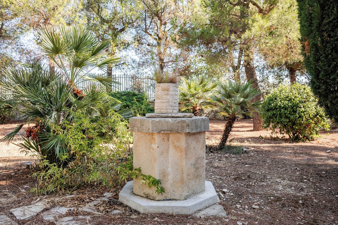 Un monument de pierre situé dans un parc, entouré d’arbres et d’arbustes.