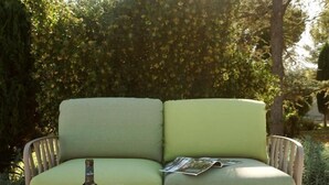 A green sofa with cushions, a glass table with a wine bottle, wine glasses, a charcuterie board with meats, cheese, and fruits.