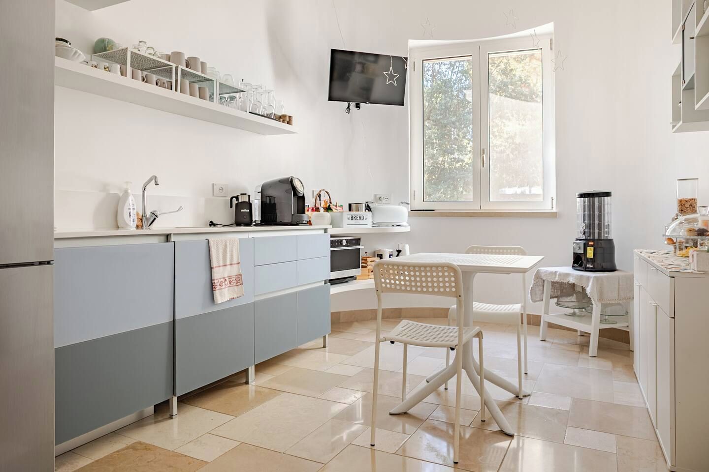 Una cucina moderna con forno a incasso, macchina del caffè e zona pranzo con tavolo e sedie.