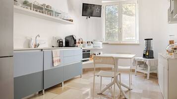 Una cucina moderna con forno a incasso, macchina del caffè e zona pranzo con tavolo e sedie.