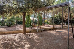 Un columpio en un jardín con árboles y arbustos.
