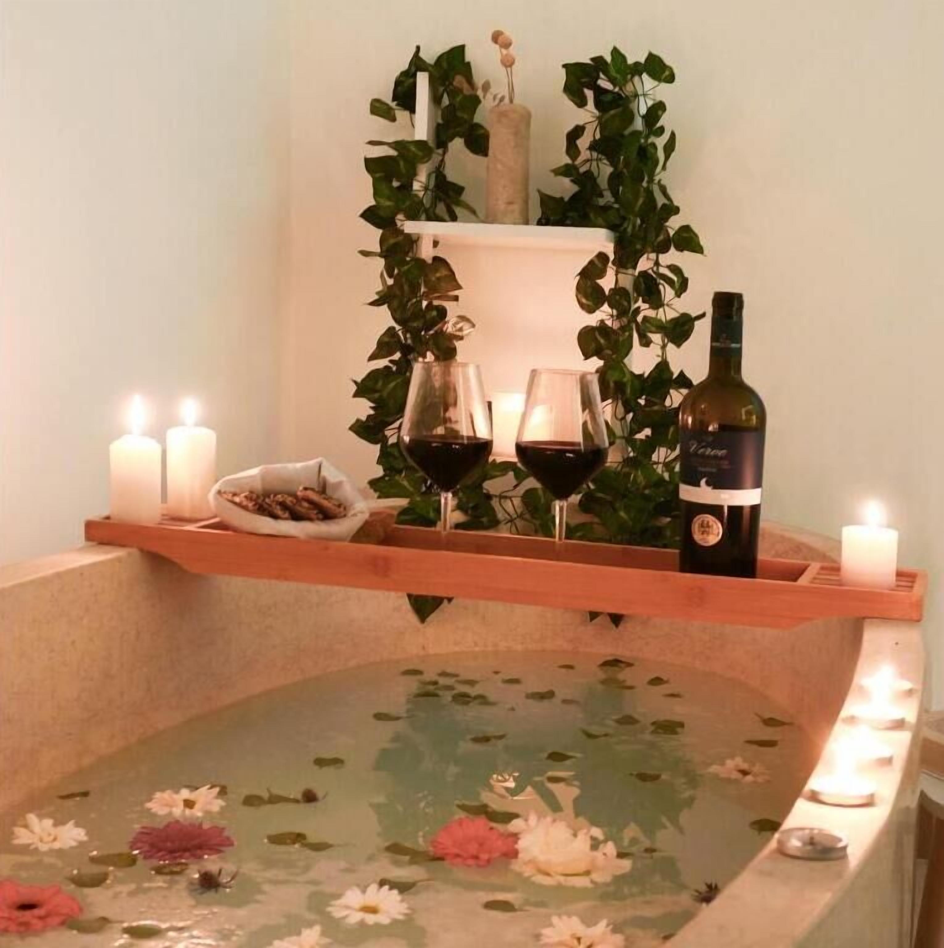 Un baño de spa con velas, una botella de vino y un bol de aperitivos.