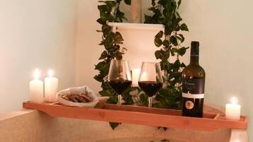 Un baño de spa con velas, una botella de vino y un bol de aperitivos.