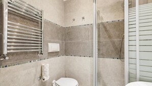 Une salle de bain comprenant des toilettes, un espace douche et une baignoire.