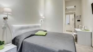 Une chambre à coucher moderne, équipée d’un lit, de lampes de chevet, d’un bureau et d’un appareil de climatisation.