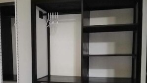 A room with a built-in shelving unit, a mirror on the left, and a marble floor.