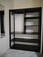 Quarto com estante embutida, espelho à esquerda e chão de mármore.