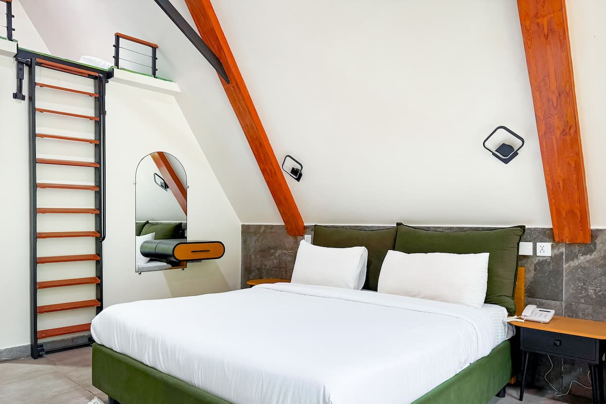 A bedroom with a bed, a bedside table, a nightstand, a wall-mounted mirror, and a wooden ladder.