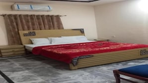 Un dormitorio con cama, mesitas de noche, ventilador de techo y ventana con cortinas.