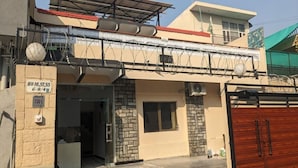 Un edificio residencial con entrada protegida por una reja, un balcón con techo rojo y una antena parabólica.