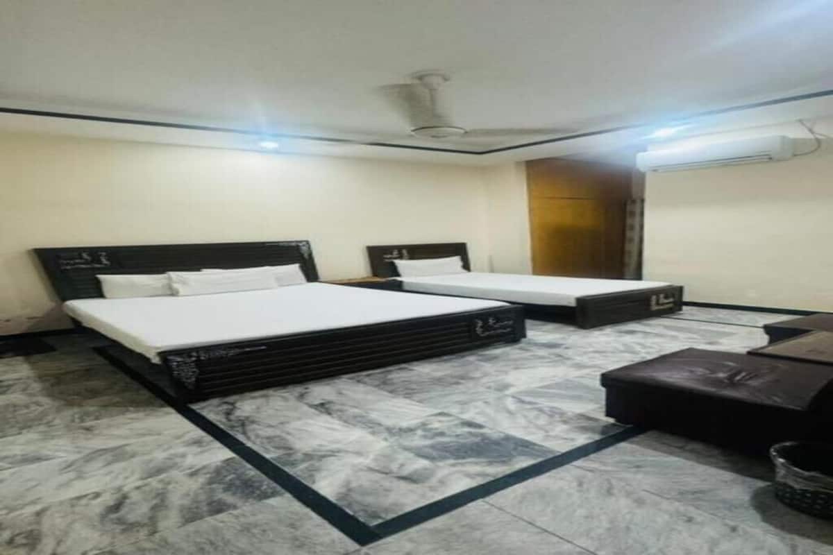A hotel room with two beds, a marble floor, a ceiling fan, and a wall-mounted air conditioner.