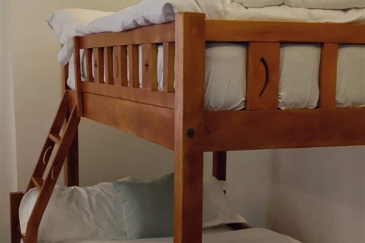 Ein Stockbett mit Holzrahmen und weißer Bettwäsche.