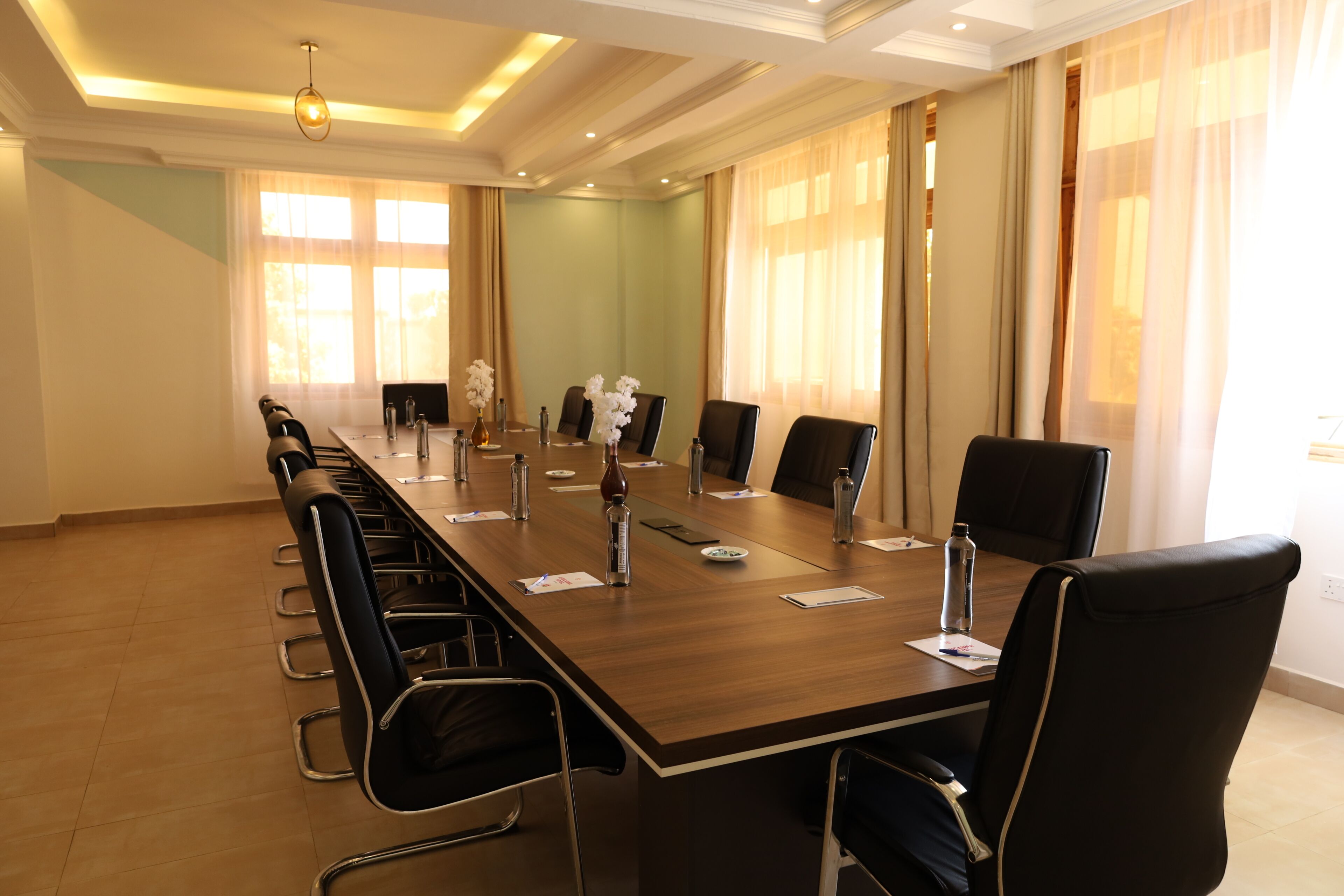 Une salle de conférence avec une longue table, des chaises et un lustre.