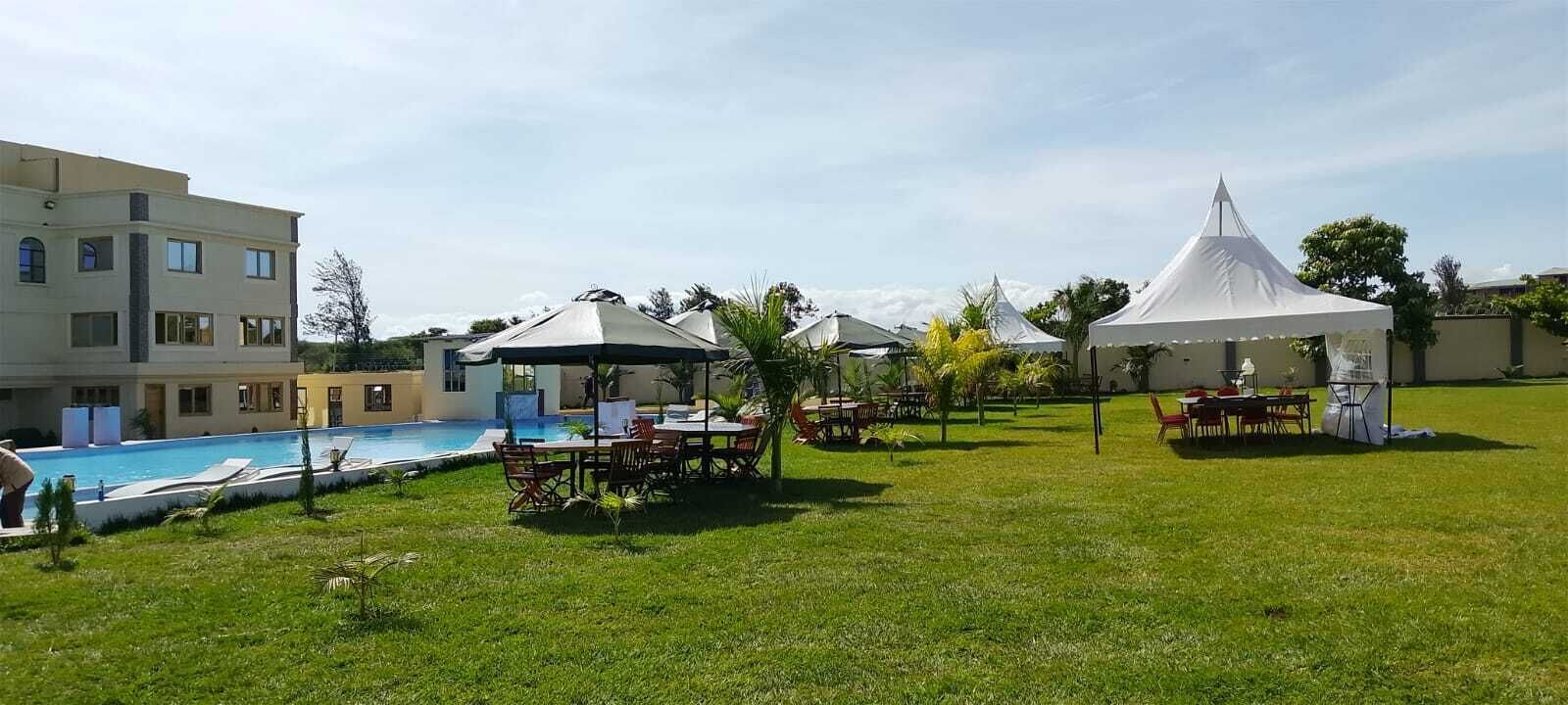 A hotel with a swimming pool, outdoor seating, and white tents.