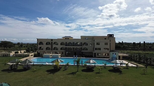 A large building with multiple balconies, a swimming pool, and surrounding greenery. - The Africana Hotel- Isiolo (Isiolo)
