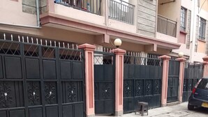 Zona residencial cerrada con entrada pavimentada, un taburete pequeño y un coche aparcado.