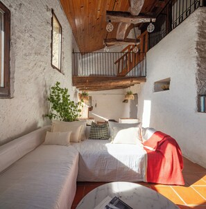 Ein rustikaler Raum mit Holzbalkendecke, einer Treppe und einem Bett mit roter Decke.