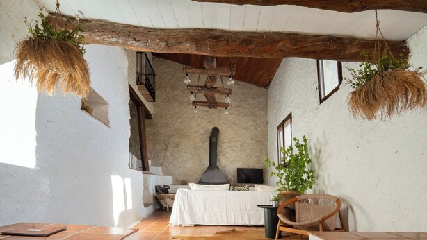 Une pièce rustique avec un mur en pierre, une cheminée, un lit et un coin repas.