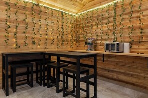 A wooden interior with a kitchen counter, bar stools, and a microwave.