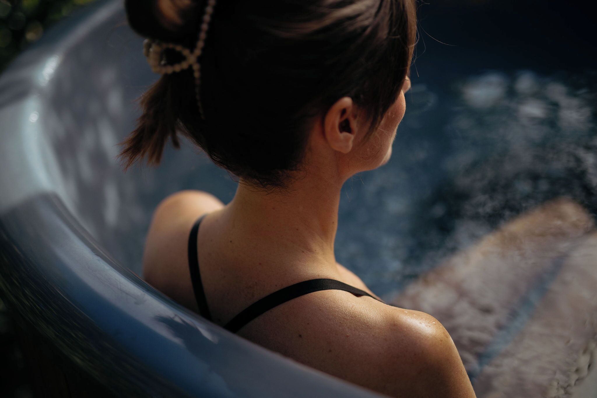 Eine Person entspannt in einer Hot Tub mit Blick auf ein Gewässer.