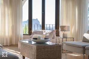 A room with a wicker ottoman, a white table, a sofa, and a lamp. - Villa COSTA AZZURRA by Abahana Villas (Benissa)