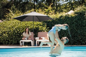 Ein Schwimmbecken mit Liegestühlen und einem Sonnenschirm.