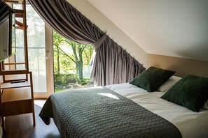 Ein Schlafzimmer mit einem Bett, Kissen, einer Holzleiter und Blick auf Bäume durch ein Fenster.