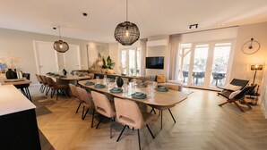Un comedor moderno con una mesa ovalada grande dispuesta para seis personas, rodeada de sillas con cojines.