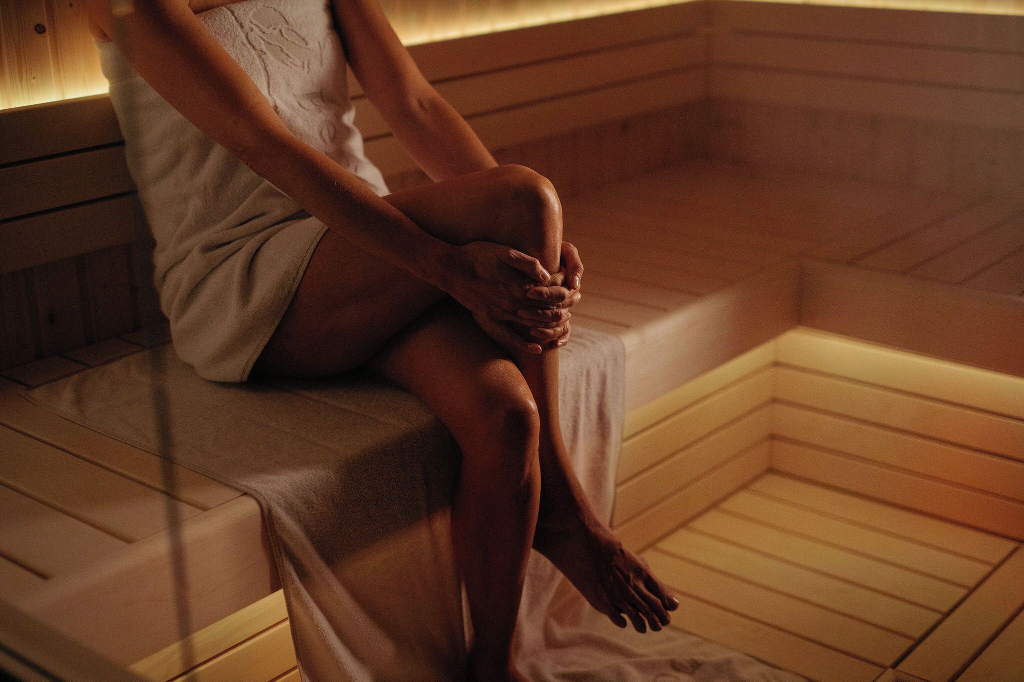Eine Person sitzt auf einer Holzbank in einer finnischen Sauna.