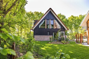 Ett modernt hus med ett sluttande tak, stora fönster och en grund av tegel.