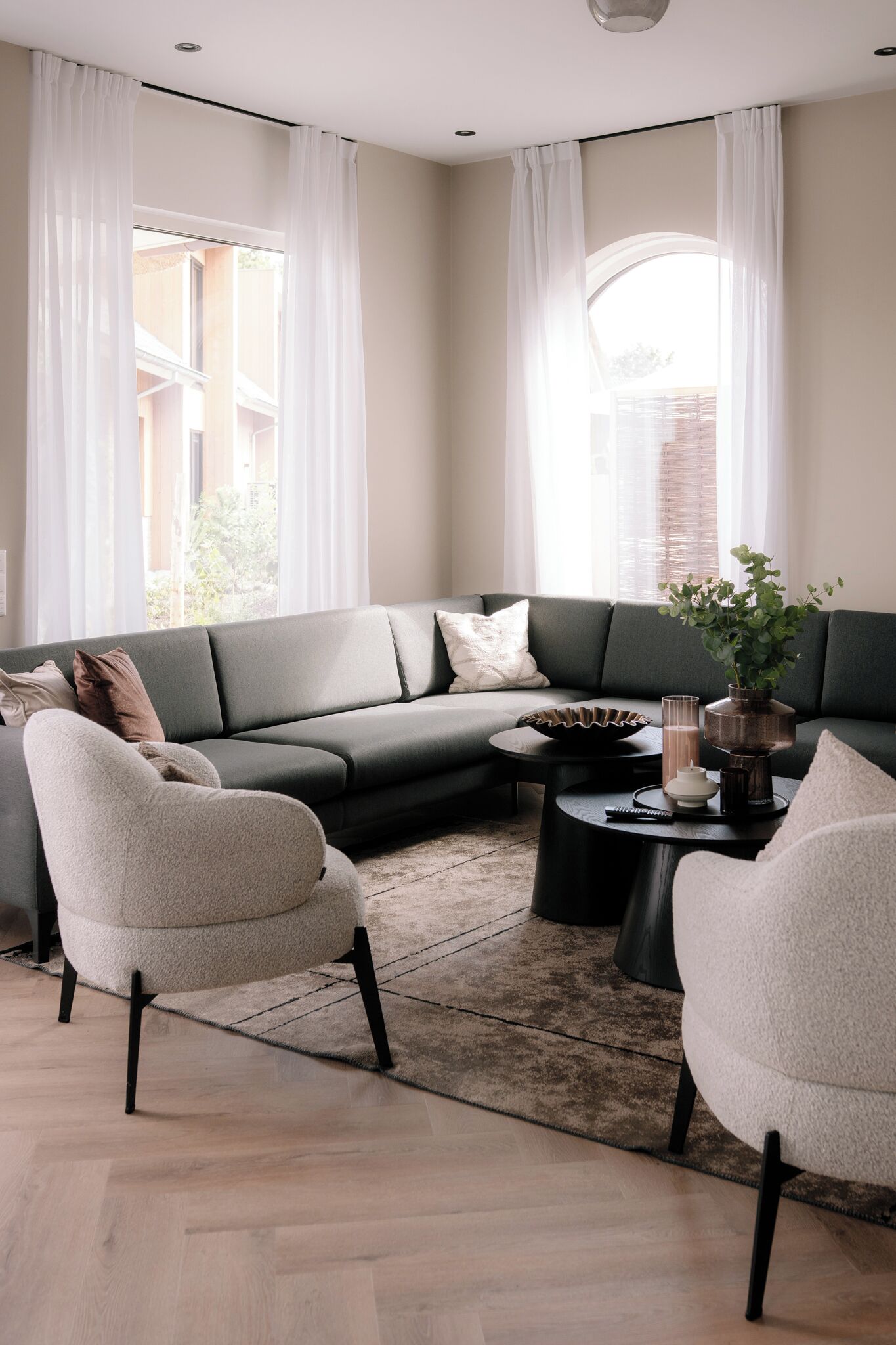 En moderne stue med en hjørnesofa, to lænestole, et sofabord og en potteplante.