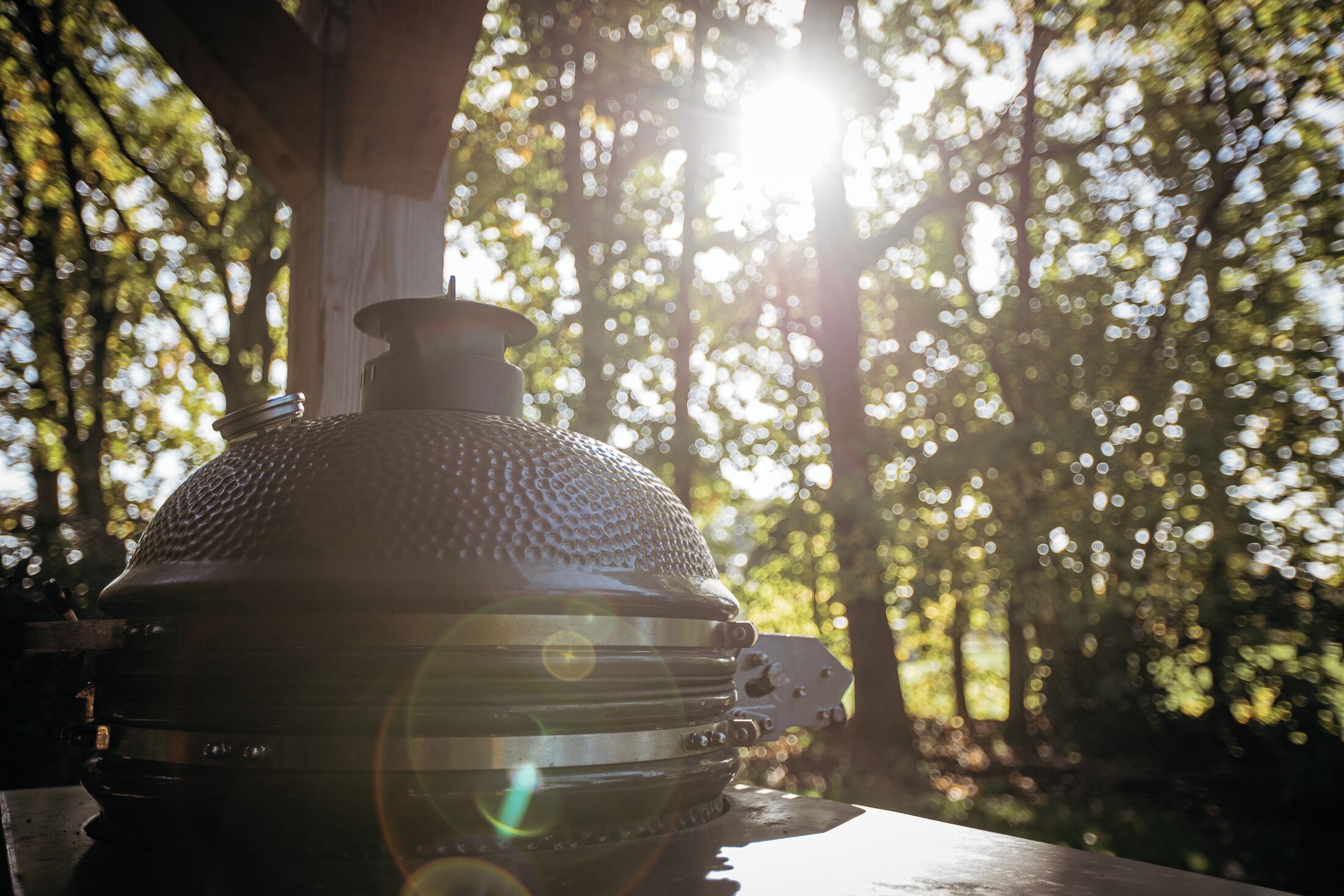 Un barbecue installé à l’extérieur, avec la lumière du soleil filtrant à travers les arbres.