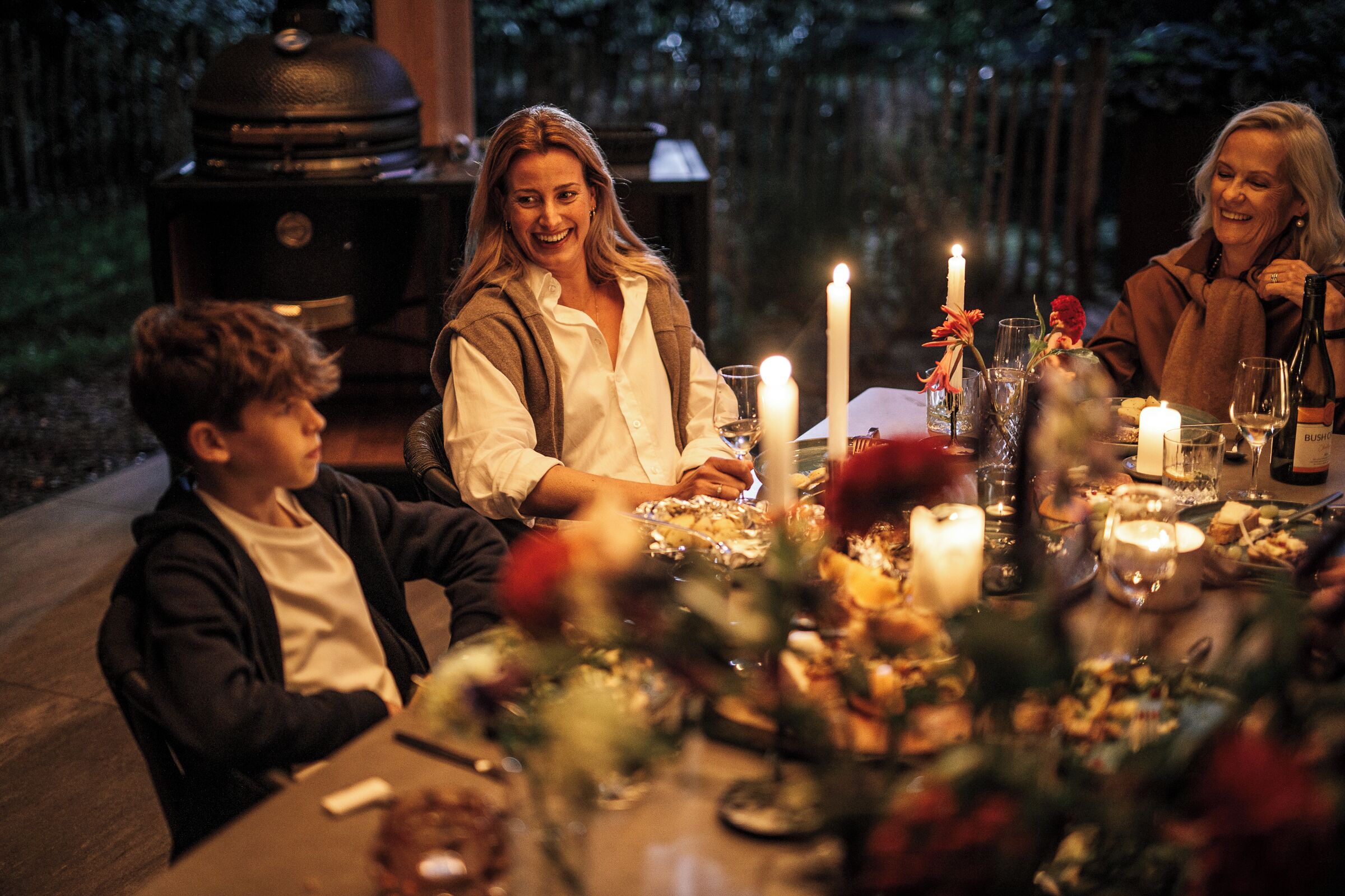 Une table à manger dressée pour quatre personnes, avec des bougies, des verres et une bouteille.