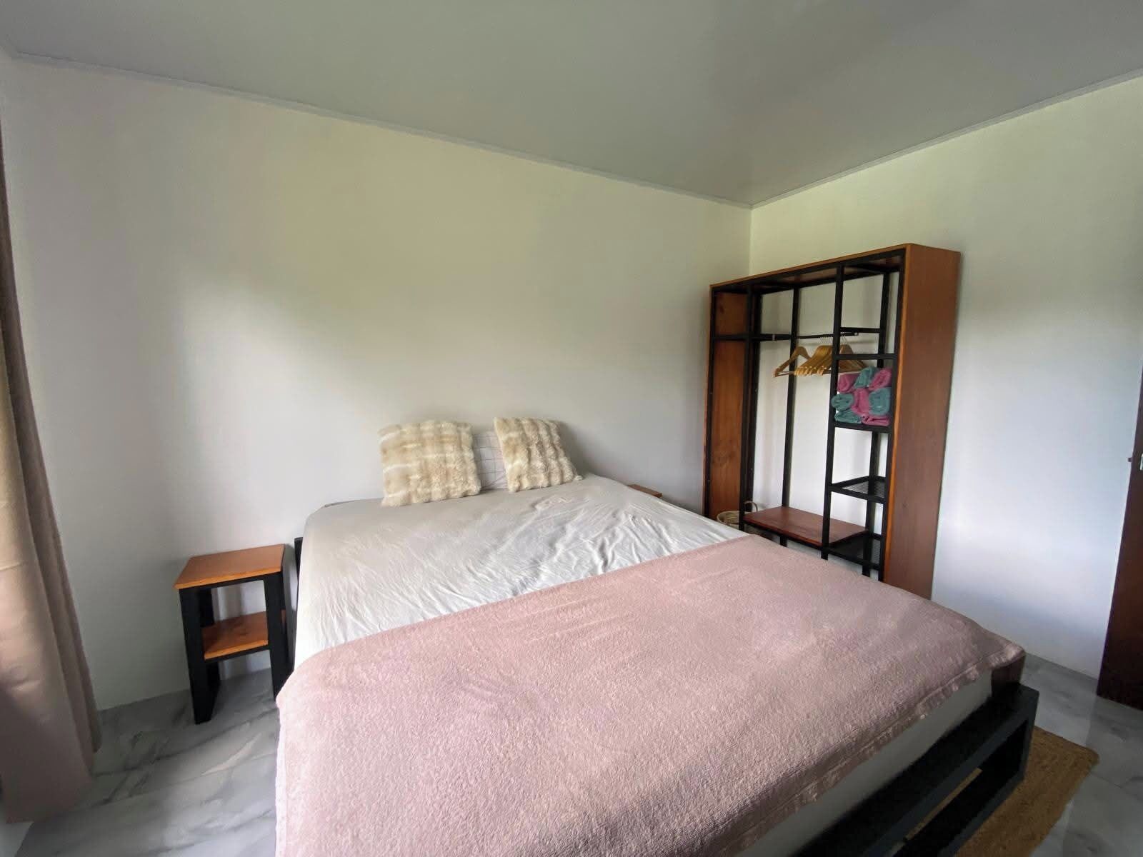 Une chambre à coucher avec un lit, une armoire en bois, une petite table et un banc.