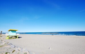 Ein Strand mit einem Rettungsturm, sandigem Ufer und ruhiger See.