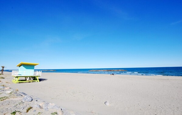 Ein Strand mit einem Rettungsturm, sandigem Ufer und ruhiger See.