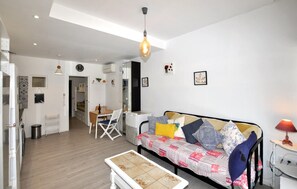 Ein kompakter Wohnbereich mit einer Couch, einem Esstisch und einer kleinen Küchenzeile.