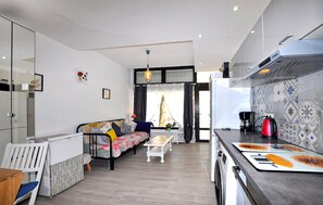 Ein kompakter Wohnraum mit Küchenzeile, Sofa, Esstisch und einer Bank.