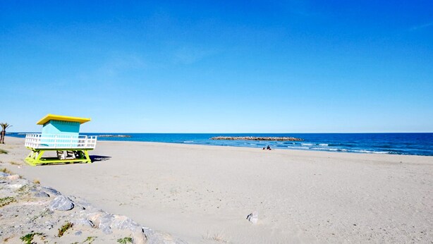 A beach with a lifeguard tower, clear blue sky, and calm sea. - Stunning apartment in Saint-Cyprien Plage (Saint-Cyprien Plage)
