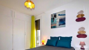 A bedroom with a bed, a painting, a lamp, and a wall with decorative stones. - Stunning apartment in Saint-Cyprien Plage (Saint-Cyprien Plage)