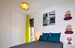 Ein Schlafzimmer mit einem Bett, einem Gemälde, einer Lampe und einer Wand mit dekorativen Steinen.