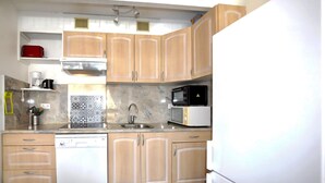 A kitchen with wooden cabinets, a dishwasher, a microwave, and a coffee maker. - Stunning apartment in Saint-Cyprien Plage (Saint-Cyprien Plage)