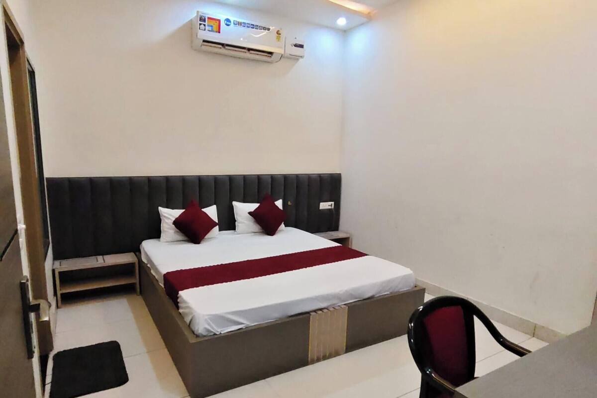 Ein Hotelzimmer mit Bett, Schreibtisch, Stuhl, Klimaanlage und Deckenventilator.