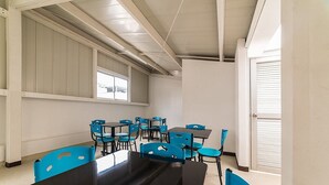 Ein Konferenzraum mit langem Tisch und blauen Stühlen, großen Fenstern und einer Tür mit Jalousien.