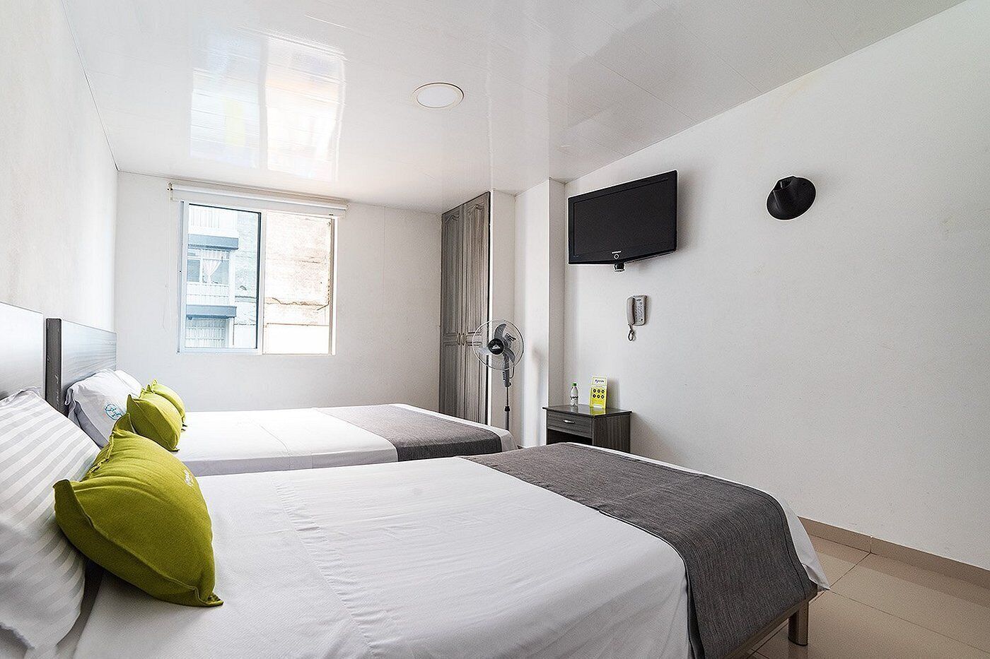 Ein Hotelzimmer mit zwei Betten, einem Fernseher, einem Ventilator und einem Fenster mit Blick.