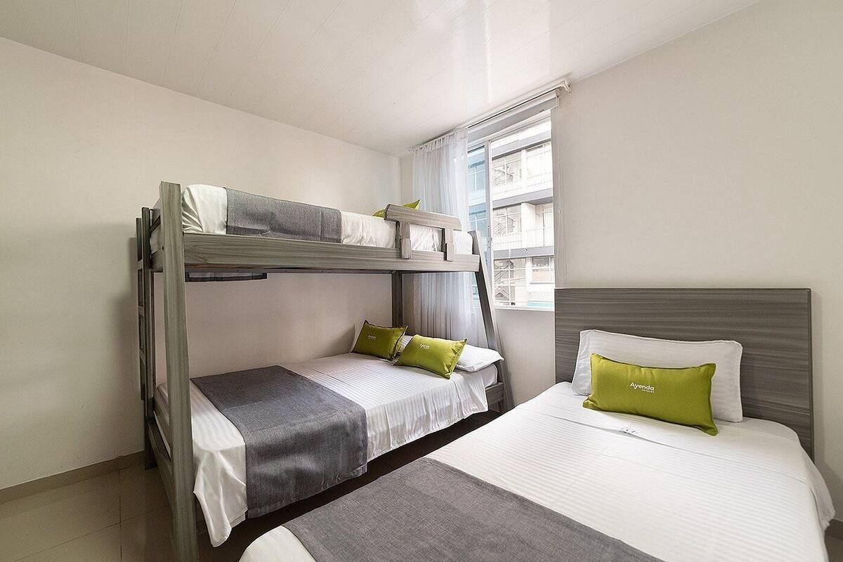 A room with bunk beds, a single bed, and a window with curtains.