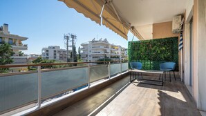 Varanda com vista para edifícios, uma parede verde e duas cadeiras.