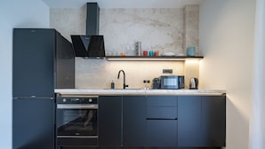 Cozinha moderna com forno embutido, máquina de café e pia.