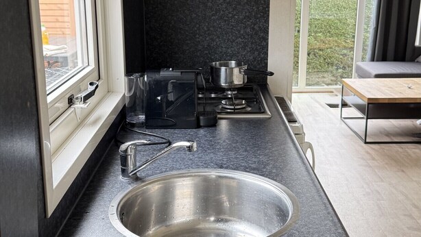 Una cocina moderna con un lavamanos de acero inoxidable, una estufa y una ventana.
